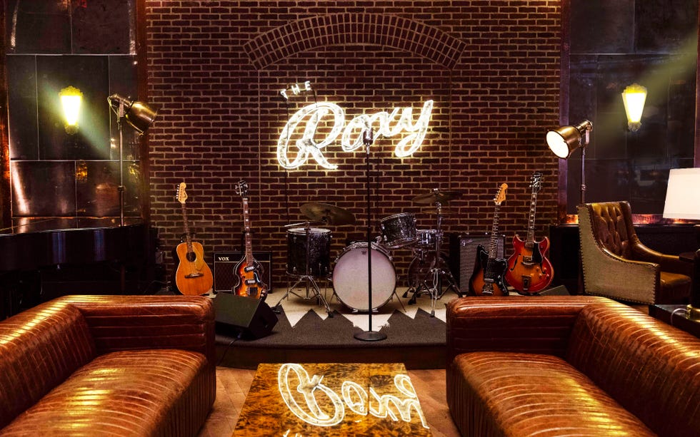 a room with a brick wall and a drum set and a couch at roxy hotel