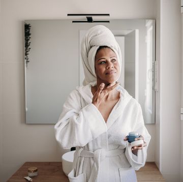 woman applying moisturizer on face in bathroom