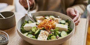 woman eats from bowl of tofu in cafe