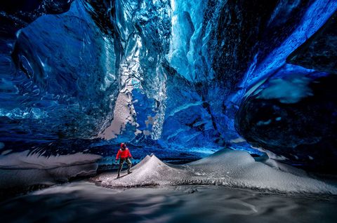 Een hiker staat in een ijsgrot in de Vatnajkullgletsjer op IJsland