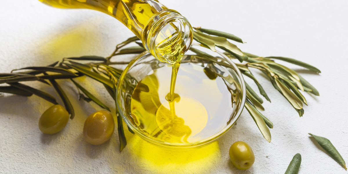 high angle view of olive oil pouring in bowl on table