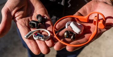 various types of wireless earphones and headphones held in two hands