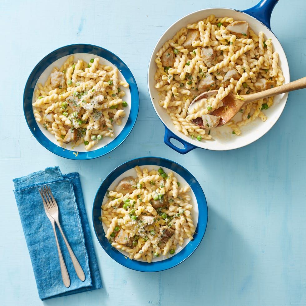 creamy lemon pasta with chicken and peas in blue bowls on a blue background