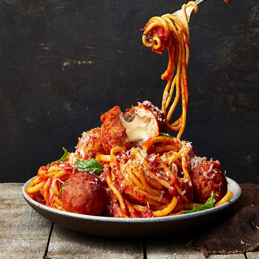 mozzarella stuffed turkey meatballs in pasta in a bowl being twirled and lifted with a fork