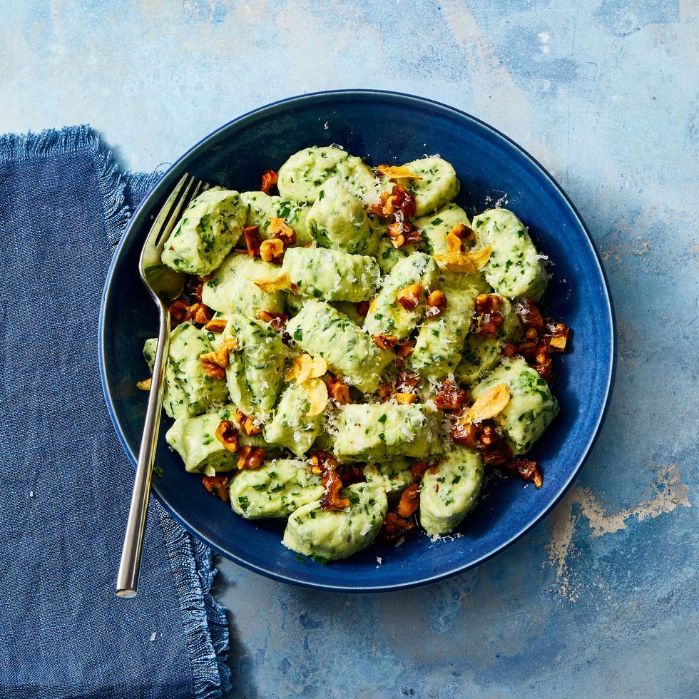 ricotta gnocchi with toasted garlic and walnuts in a blue bowl on a blue background