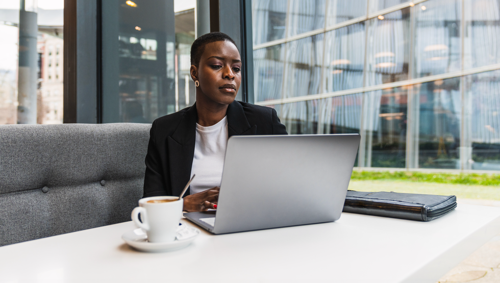 a person sitting at the table with a laptop and coffee