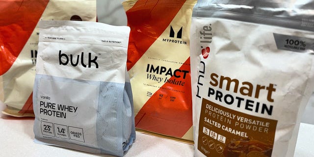 four different bags of protein powder on a kitchen surface