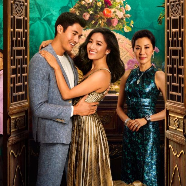 rachiel and nick hug while nick's mother looks on disapprovingly in a promotional image for crazy rich asians