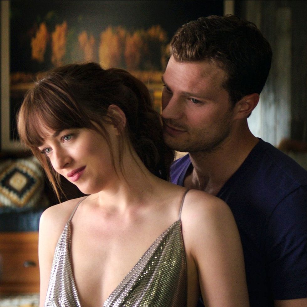 christian hugs anastasia from behind affectionately in a scene from fifty shades of grey