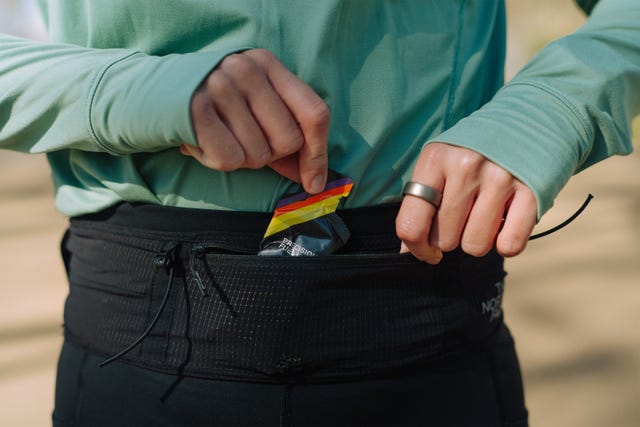 close up of a woman getting an energy gel out of a running belt