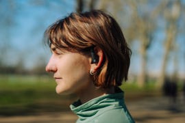 person wearing wireless earbuds in a park