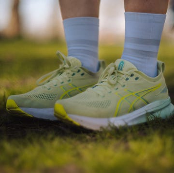 a pair of legs wearing green asics running shoes and white quarter length socks, stood on grass a pair of legs wearing green asics running shoes and white quarter length socks, stood on grass