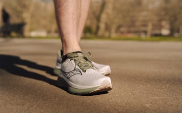 close up of a person's lower leg wearing green and grey running shoes