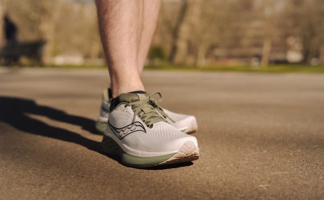 close up of a person's lower leg wearing green and grey running shoes
