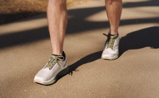 a pair of legs wearing saucony running shoes stood on tarmac