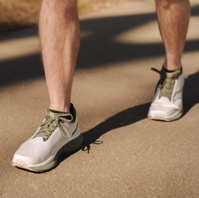a pair of legs wearing saucony running shoes stood on tarmac a pair of legs wearing saucony running shoes stood on tarmac
