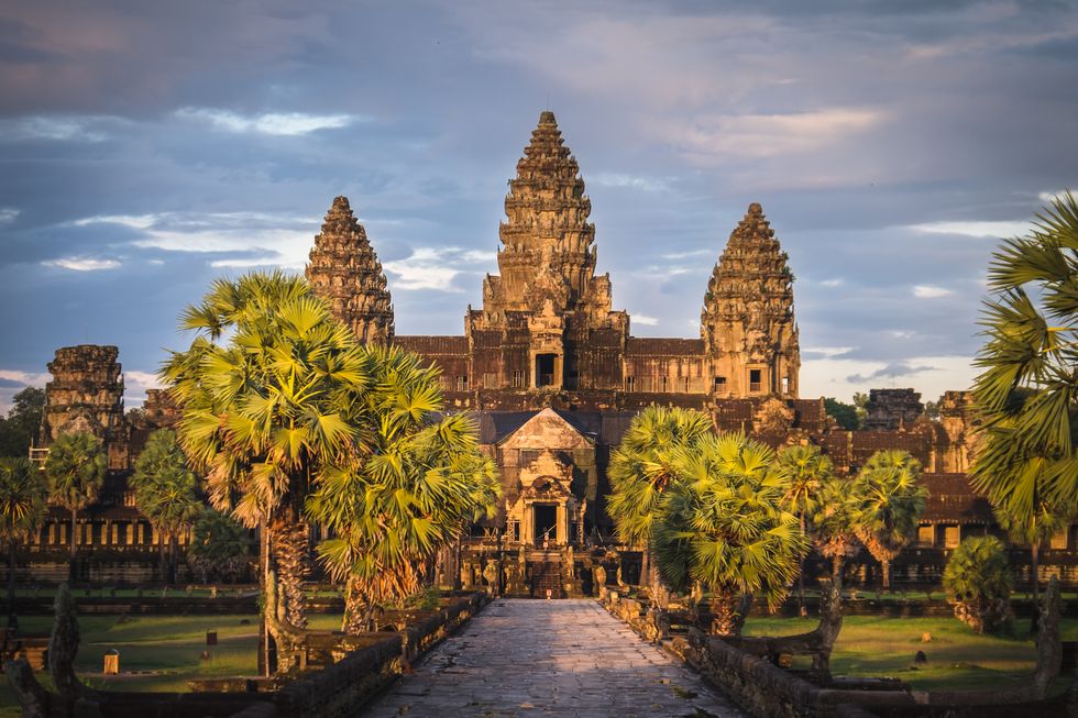 a large building with towers and trees with angkor wat in the background