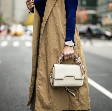 close up on businesswoman's hand with a smart watch while holding a bag wearing a sleeveless coat