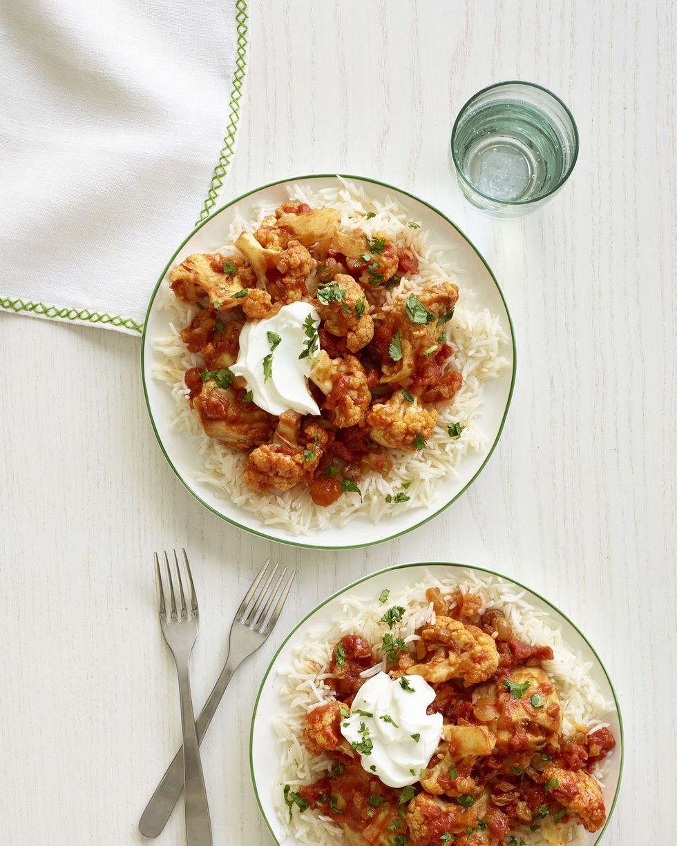 slow cooker indian spiced chicken and cauliflower on two plates with two forks