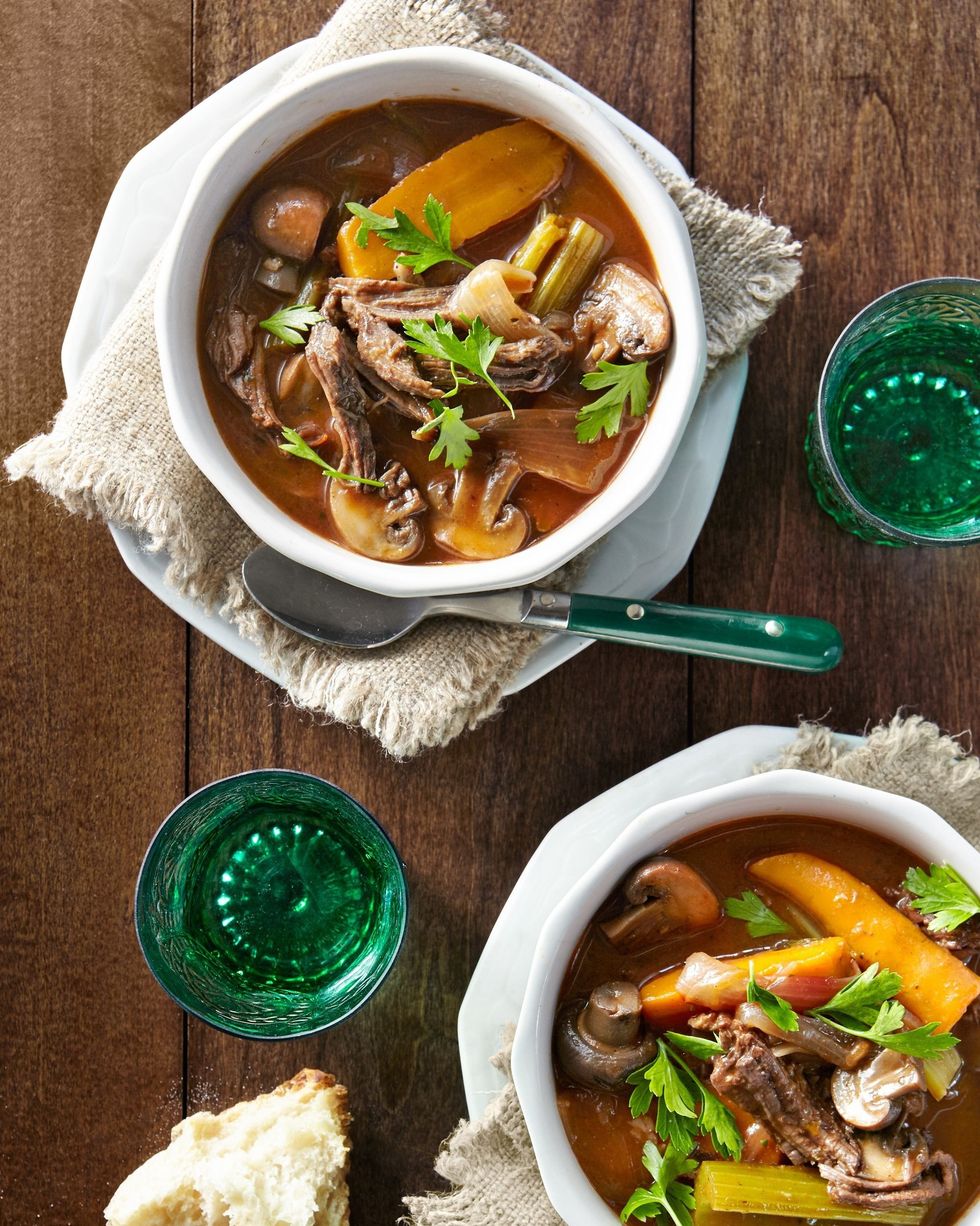slow cooker red wine beef stew in two white bowls with green cups and spoons
