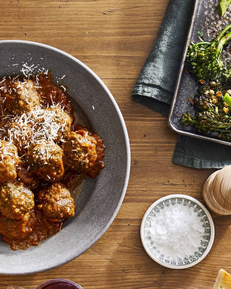 slow cooker spinach parmesan meatballs piled on a metal plate and topped with shredded parmesan