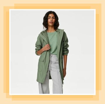 woman in trousers top and green raincoat