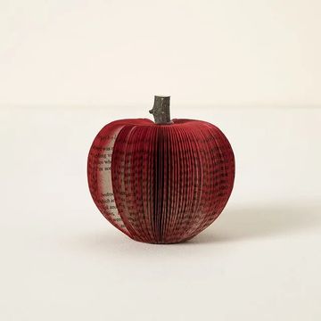 a red paper apple made from book pages with a wooden stem from a tree
