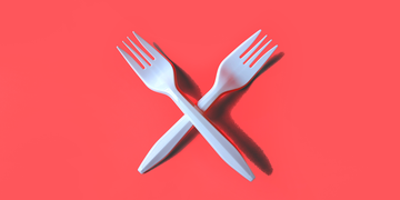 two white plastic forks on red background