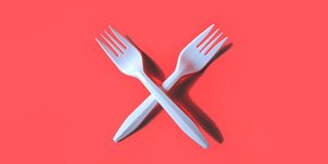 two white plastic forks on red background
