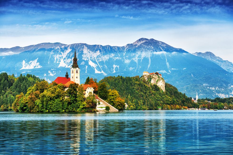 lake bled located in slovenia europe there is a church on the island and ancient castle on top of a rock beautiful blue sky with dramatic cloudscape over the reflection in the bled lake story in such a beautiful sunny day on sunset european alps in the background