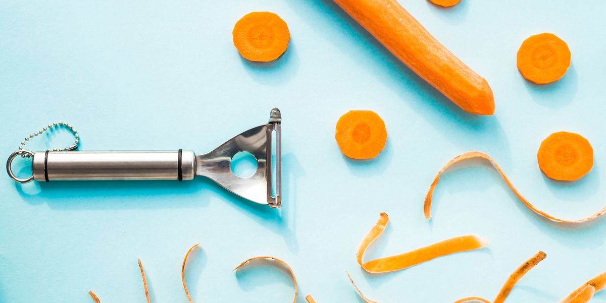carrot cleaning with a special kitchen appliance on a blue background bright carrot shavings and rings top view, flat lay