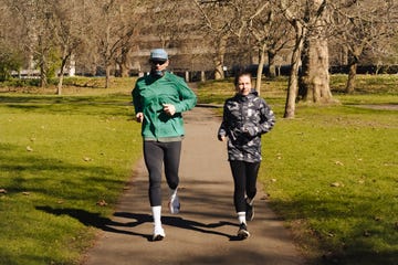a man and a woman running side by side down a path, wrapped up in waterproof jackets