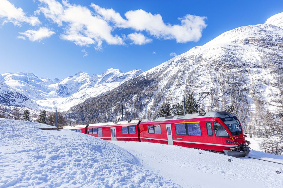 bernina express train in the snowy landscape of bernina pass at day, canton of graubunden, engadin, switzerland
