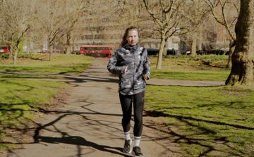a woman jogging through a park wearing black leggings and a waterproof jacket