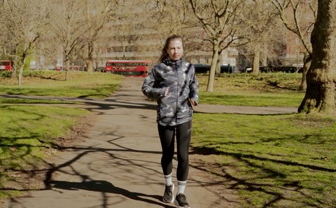 a woman jogging through a park wearing black leggings and a waterproof jacket