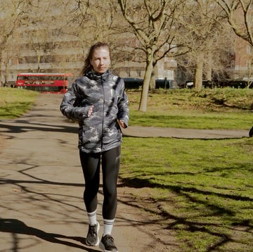 a woman jogging through a park wearing black leggings and a waterproof jacket a woman jogging through a park wearing black leggings and a waterproof jacket