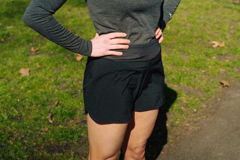 close up of a women's torso in the park wearing black shorts and a grey long sleeve top