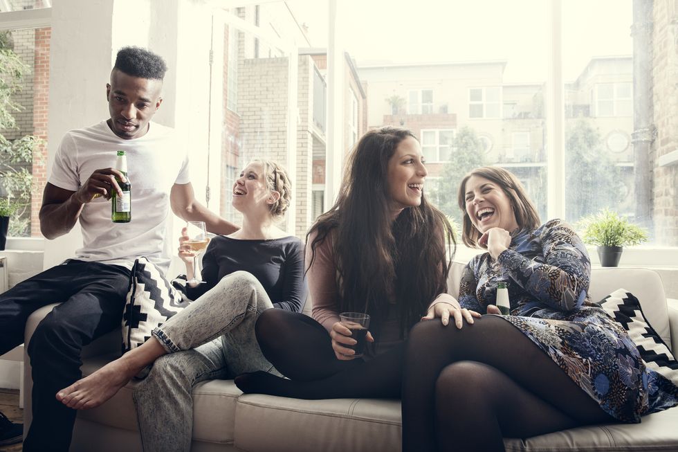 group of young people having a party, telling jokes, having a good time, celebrating, in a private home