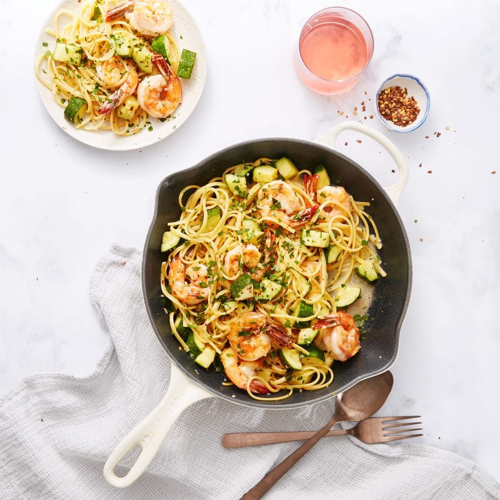 shrimp and zucchini scampi in a white skillet and on a white plate on a white background