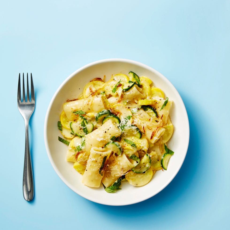 summer squash, mint, and pecorino pasta in a white bowl on blue background