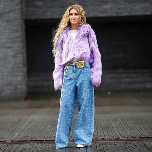 copenhagen, denmark february 01 emili sindlev wears blue earrings, a pale purple large fluffy fur jacket, a white t shirt, a purple shiny leather quilted timeless handbag from chanel, a gold shiny leather flower buckle belt, blue with white painted logo and polka dots print pattern denim wide legs pants from chanel, white shiny leather pointed pumps heels shoes , outside a roege hove, during the copenhagen fashion week autumnwinter 2023 on february 01, 2023 in copenhagen, denmark photo by edward berthelotgetty images