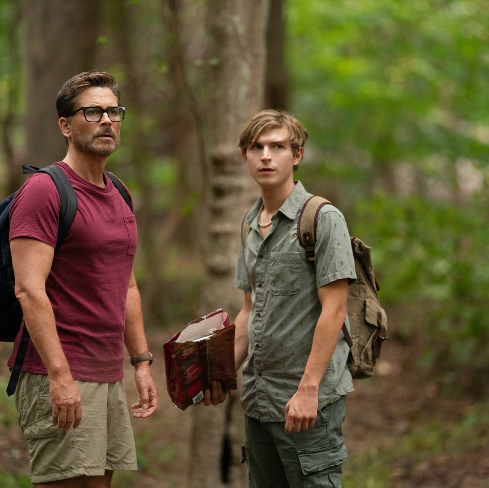 a father and son search the woods for a lost dog in a scene from dog gone, a good housekeeping pick for bet kids' movies 2023