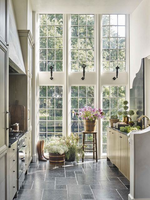 a wall of windows brings in natural light to a galley kitchen with stone countertops and floors