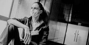 a healthcare worker looks out the window wearing a mask