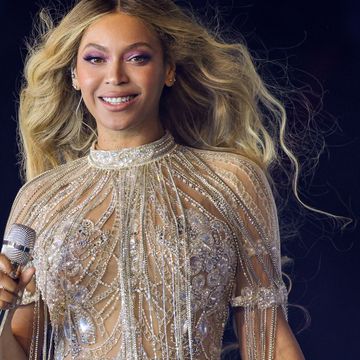 beyonce smiles at the camera, she holds a microphone in one hand and wears a beaded dress with short sleeves and beaded fringe