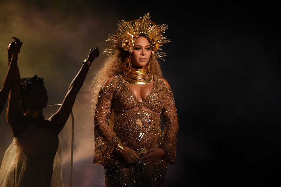 beyoncé performing on a stage while wearing a ﻿jewel encrusted gown and golden headpiece