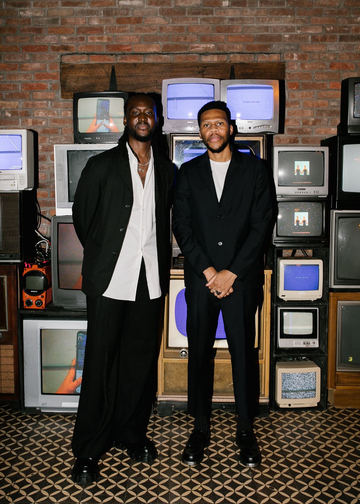 blacktag founders ousman sahko and akin adebowale standing in front of a wall of old tvs