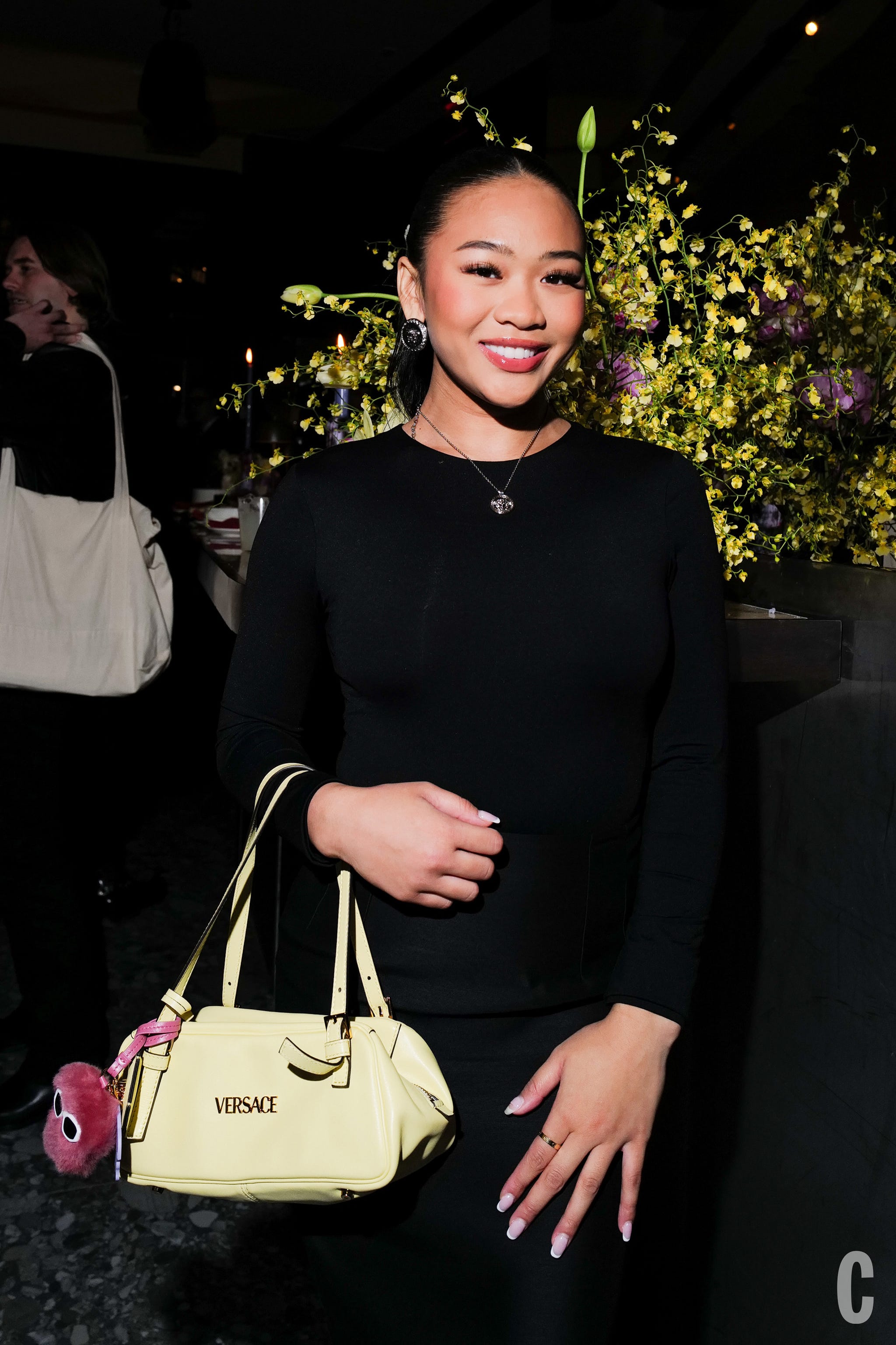 a woman in a black dress holds a yellow handbag