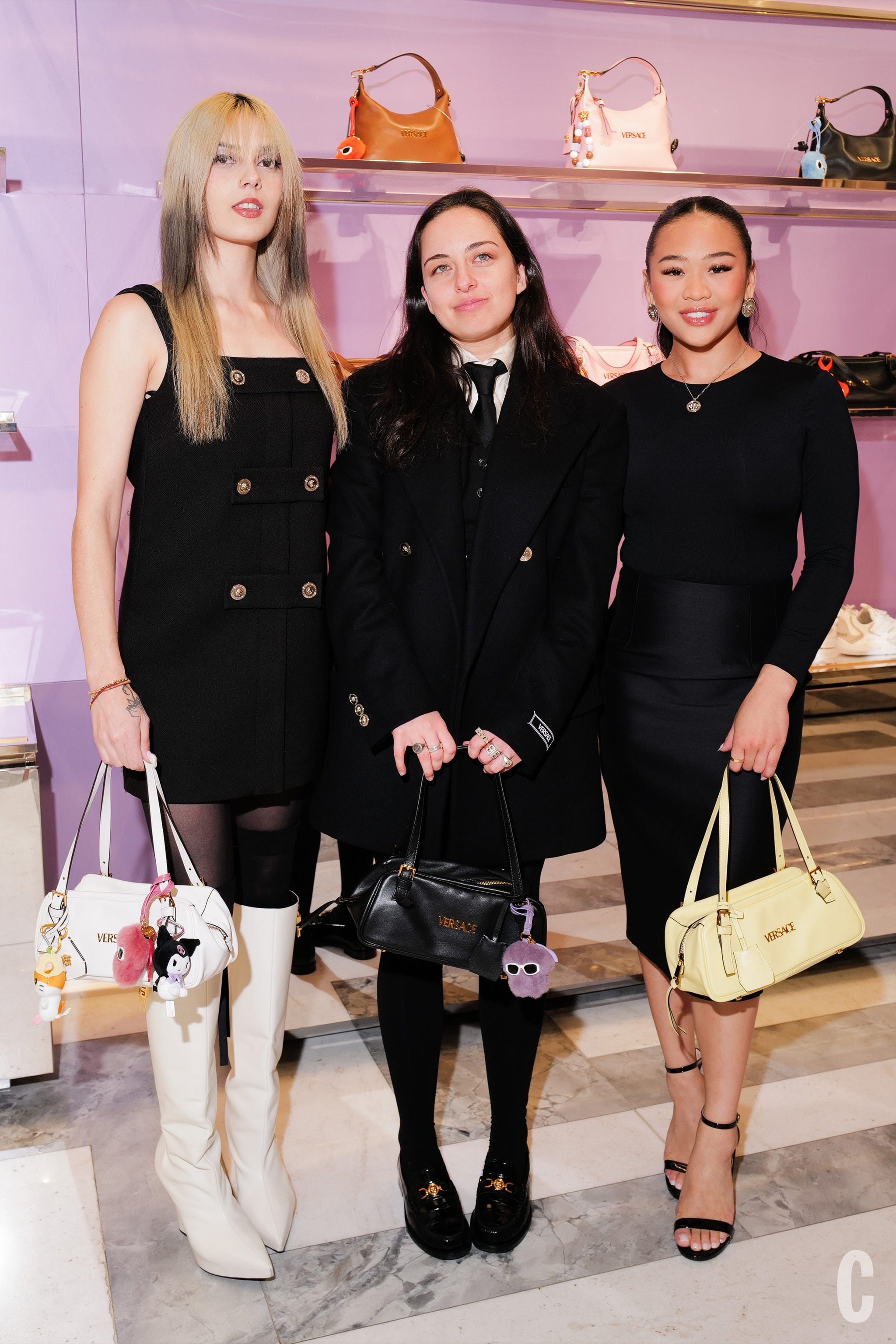 three women posing in fashionable clothes with bags