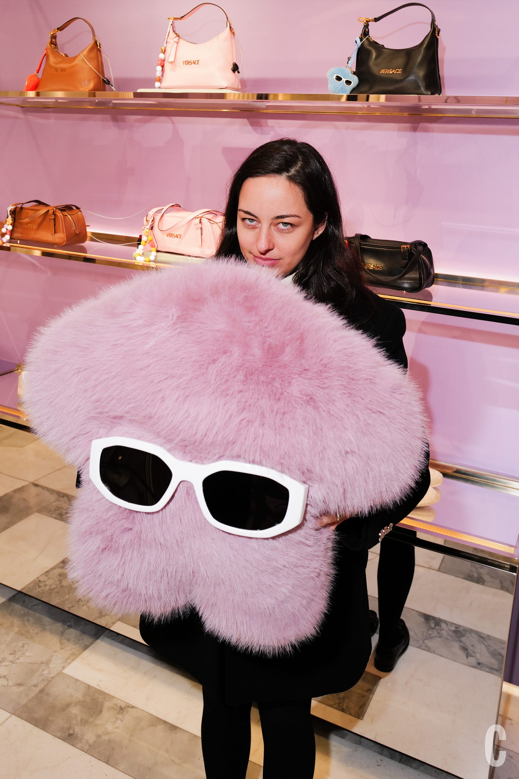 man holding large fluffy pink accessory with sunglasses in stylish retail environment